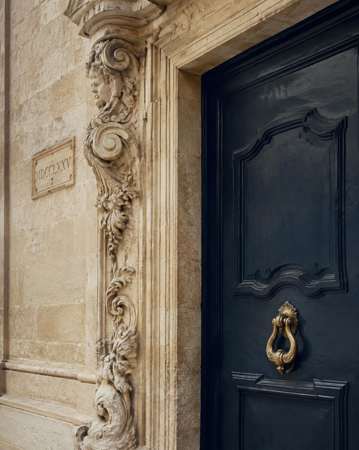 Carved baroque limestone doorway with a navy door in Valletta